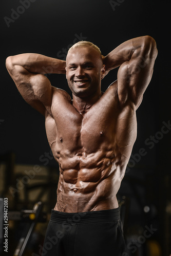 Handsome strong athletic men pumping up muscles workout fitness and bodybuilding concept background - muscular bodybuilder fitness man doing abs exercises in gym naked torso.