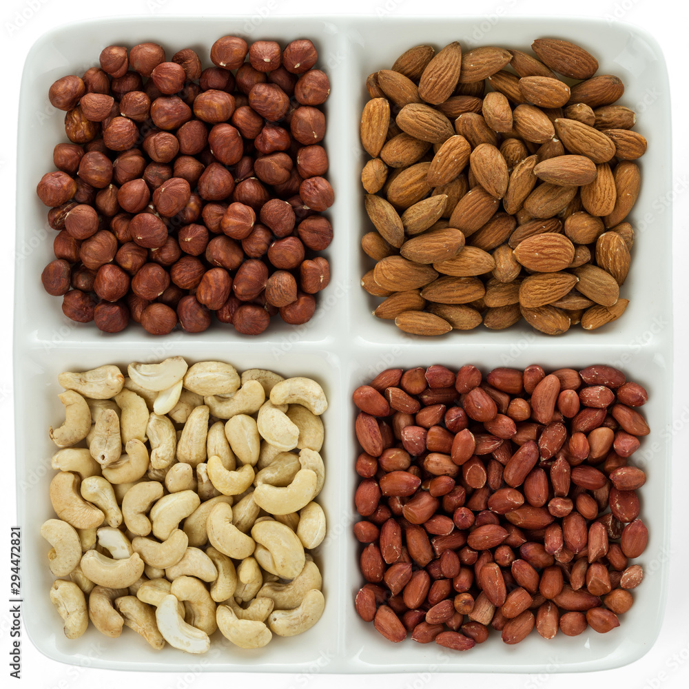 Four kinds of nuts in four compartments of combination plate: cashews, peanuts, hazelnuts, and almonds. Four kinds of nuts in four compartments of combination plate: cashews, peanuts, hazelnuts, and almonds.