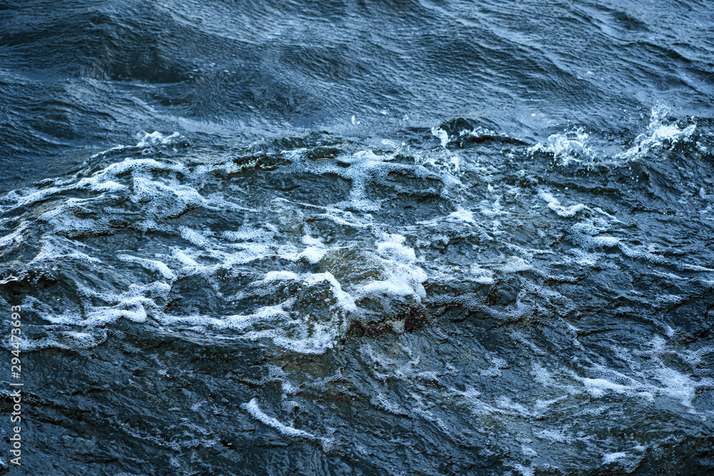 Fototapeta premium Aerial view to ocean waves. Blue water background. Abstraction of sea foam in the ocean. Dark water, storm waves