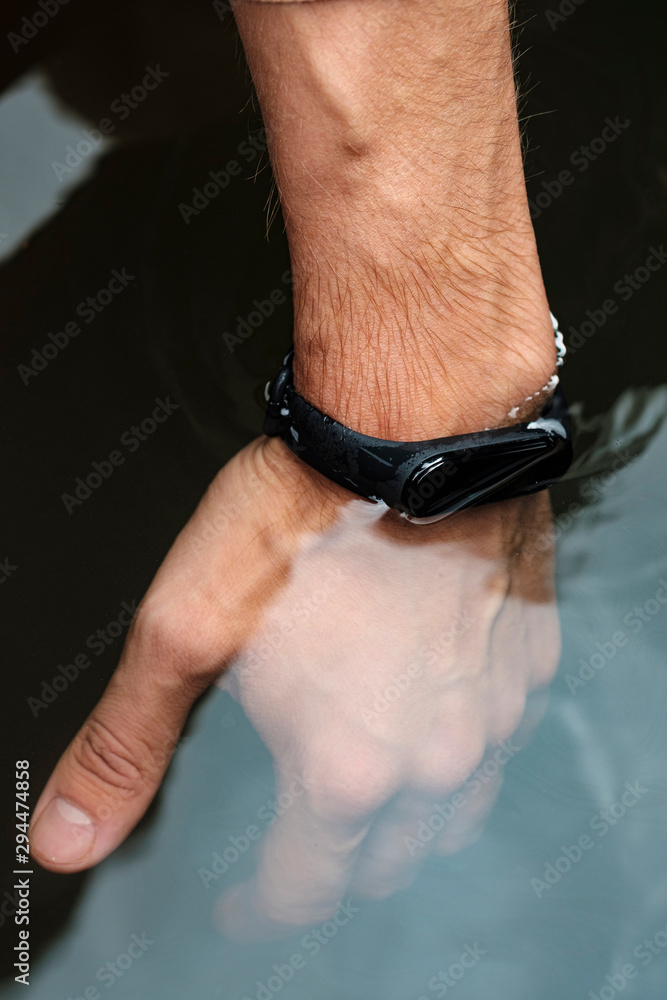 Waterproof fitness bracelet on a male hand. Check smart bracelet for water resistance. Male hand in the water. Modern technologies. Smart lifestyle concept. Waterproof fitness bracelet on a male hand. Check smart bracelet for water resistance. Male hand in the water. Modern technologies. Smart lifestyle concept.