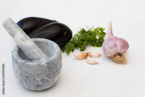 Mortar and pestle, garlic and vegetables on a white background. Healthy eating concept.
