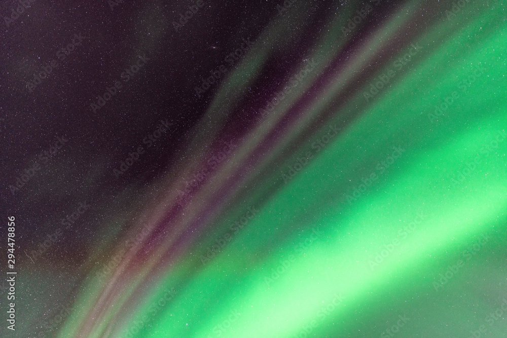 View up at Strong Northern Lights and atmospheric phenomenon 'STEVE' meets each other. Steve appears as a purple and green light ribbon at height of 450 km. Northern Sweden Scandinavia