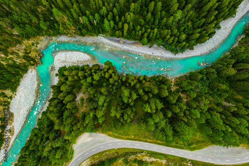 Inn River flowing in the forest in Switzerland. Aerial view from drone on a blue river in the mountains photo