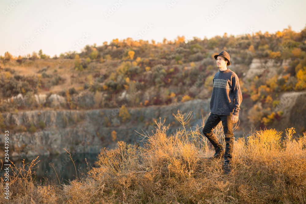 Young man traveler in black hat outdoor mountains lake on background. Autumn vacations and Lifestyle concept Young man traveler in black hat outdoor mountains lake on background. Autumn vacations and Lifestyle concept