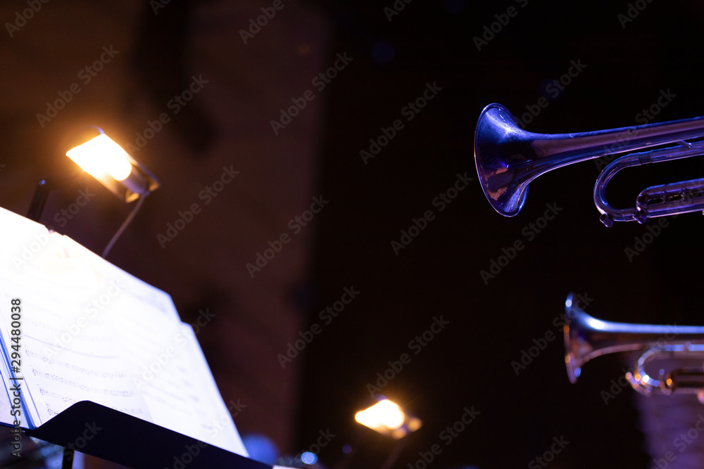 Trumpet players of a big band section playing their horns in blue stage