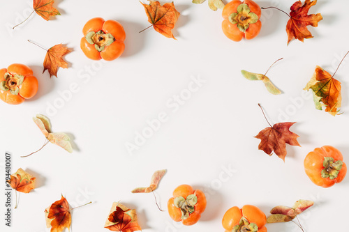 Autumn creative composition. Dried leaves, persimmon on white background. Fall concept. Autumn background. Flat lay, top view, copy space
