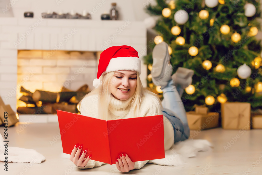 Beautiful young woman looking photobook in front of Christmas tree Beautiful young woman looking photobook in front of Christmas tree