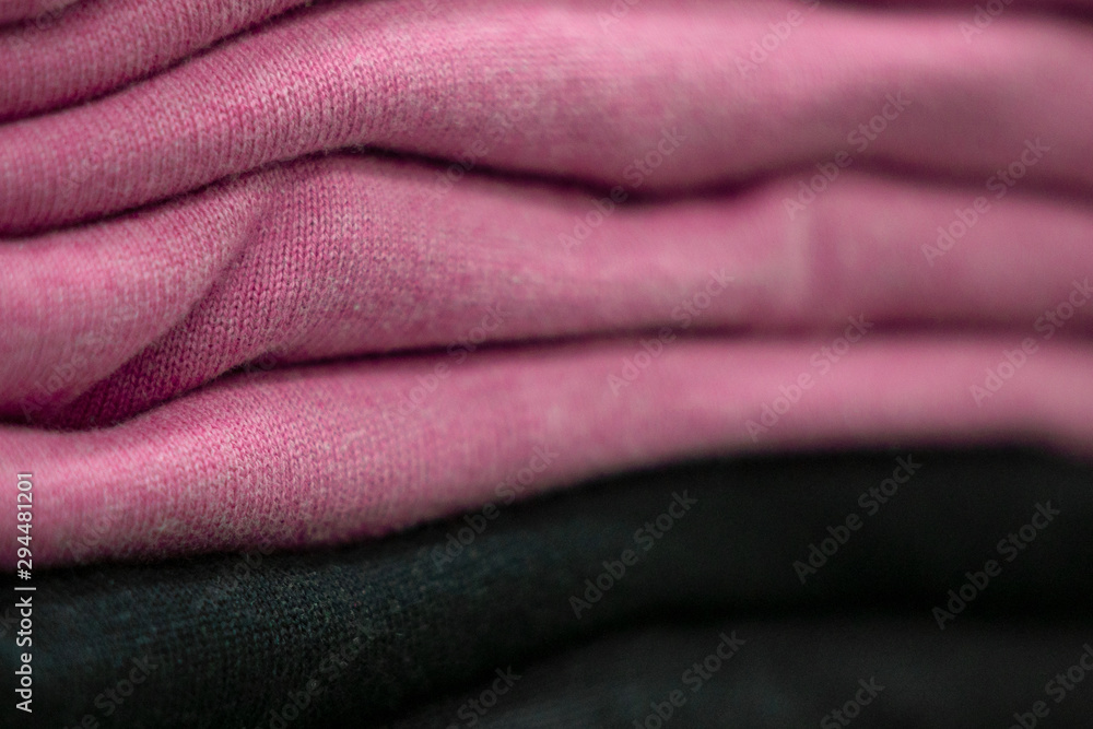 Fototapeta premium Warm clothing neatly folded on a store shelf. Sweatshirts, sweaters, jumpers, cardigans, hoodies, bobmers with piles on the shelf. Clothes storage. Size range.