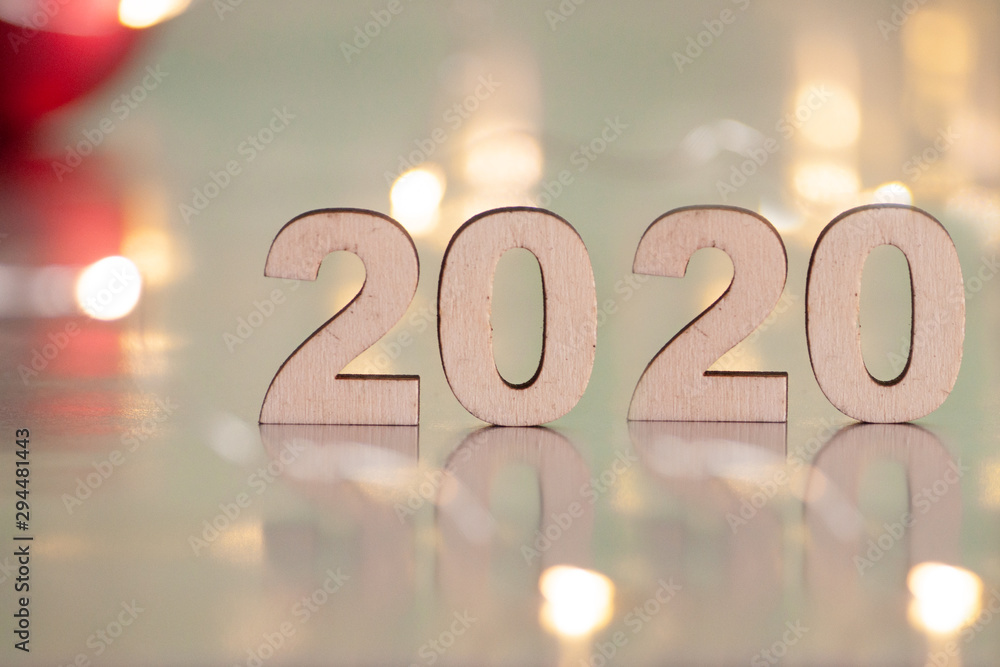 The inscription 2020, New Year and Christmas, from behind blurred dots of light on a blue background and red balls on the Christmas tree. Christmas and holiday. The inscription 2020, New Year and Christmas, from behind blurred dots of light on a blue background and red balls on the Christmas tree. Christmas and holiday.