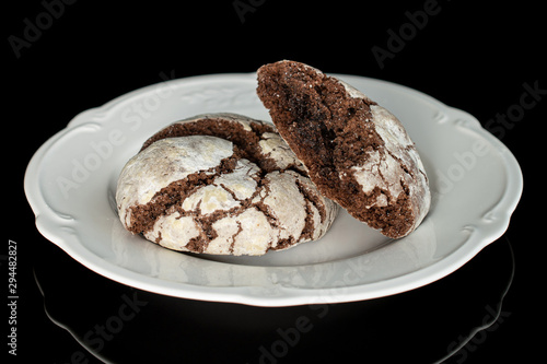Group of one whole one half of baked chocolate brownie cookie on white plate isolated on black glass