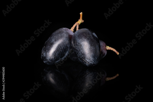 Group of three whole fresh black grape isolated on black glass