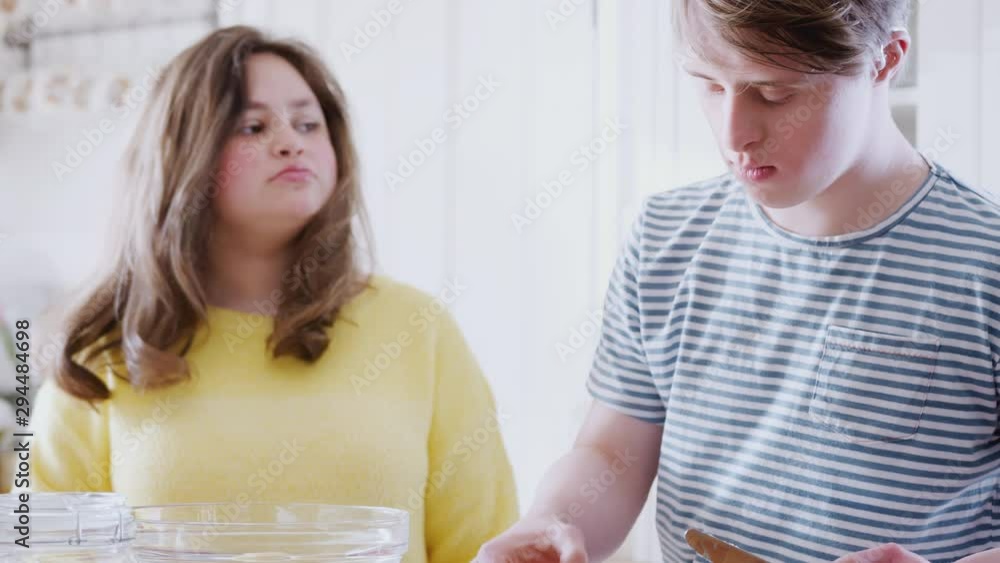 Young Downs Syndrome Couple Adding Butter To Cake Recipe They Are Baking In Kitchen At Home Young Downs Syndrome Couple Adding Butter To Cake Recipe They Are Baking In Kitchen At Home