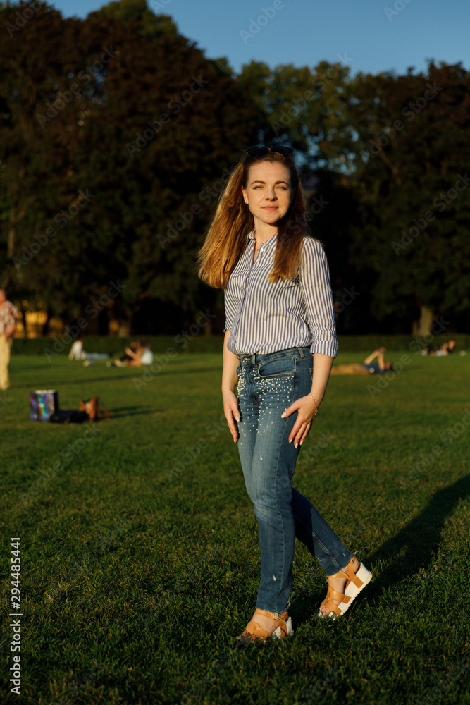 Portrait of a cute girl in the city. girl on the lawn in a city park