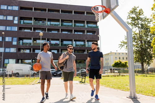 sport, leisure games and male friendship concept - group of men or friends going to play basketball outdoors