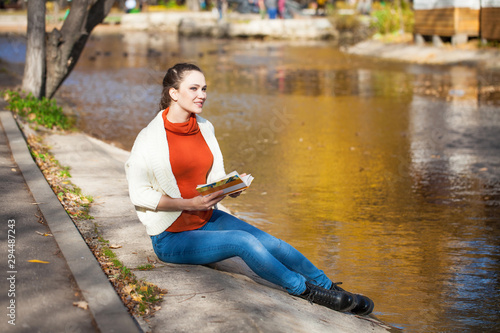 Young beautiful woman reading a book in autumn park