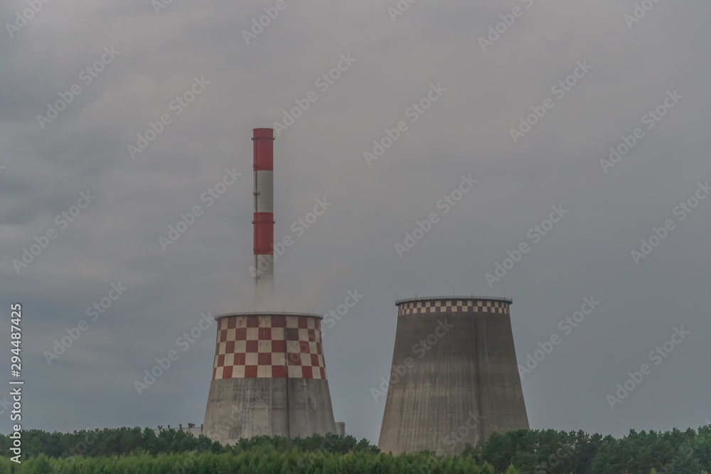 Large industrial chimneys and smoke against the sky, forests. Industrial pipes near the village in the woods