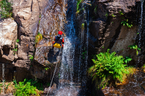 DESCENT OF WATERFALL WATERFALL WITH HANGING SCALE OF ROPES AND WATER FALLING ON ROCKS 