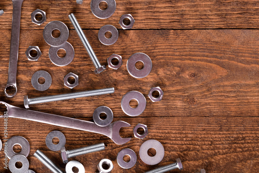 Keys wrenches, bolts, nuts, washers on a wooden background Keys wrenches, bolts, nuts, washers on a wooden background