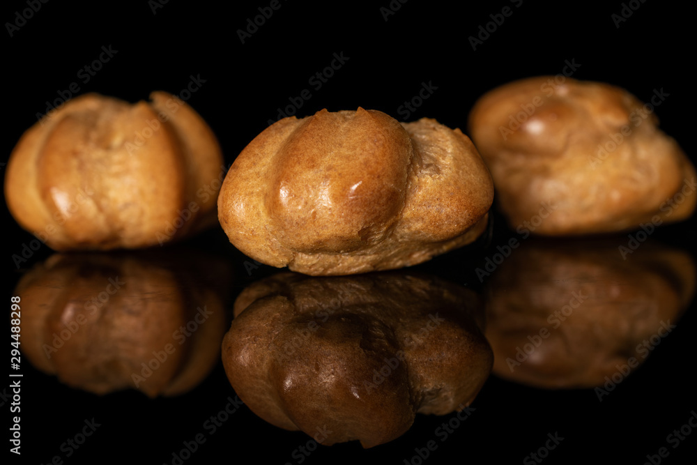 Group of three whole baked golden profiterole isolated on black glass