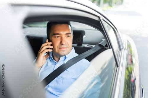 transport, communication and business concept - male passenger or businessman calling on smartphone on back seat of taxi car