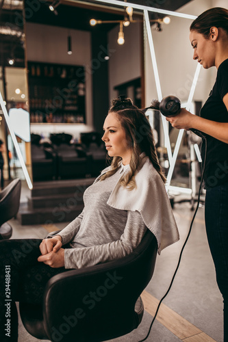 Beautiful brunette woman with long hair at the beauty salon getting a hair blowing. Hair salon styling concept.