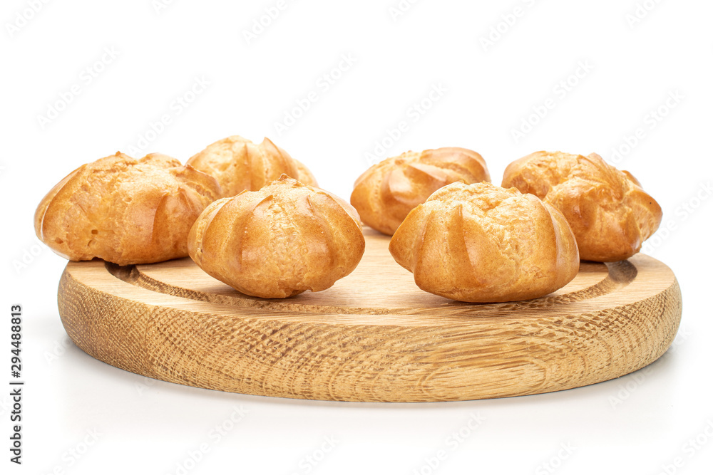 Group of six whole baked golden profiterole on bamboo plate isolated on white background