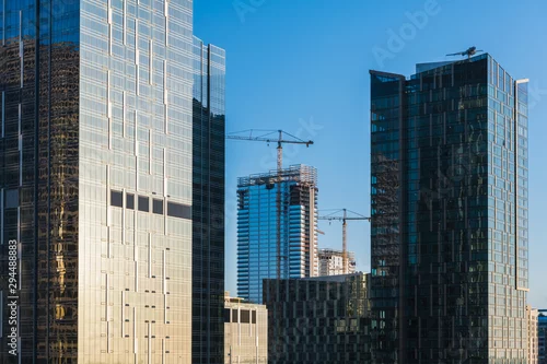 Obraz Modern skyscrapers in a downtown business district with cranes and new buildings under construction - concepts of development, progress, growth, economy, success