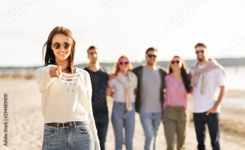 friendship, leisure and people concept - happy woman in sunglasses with group of friends on beach in summer pointing to you