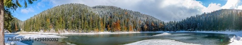 The first snow on a lake in a mountain forest