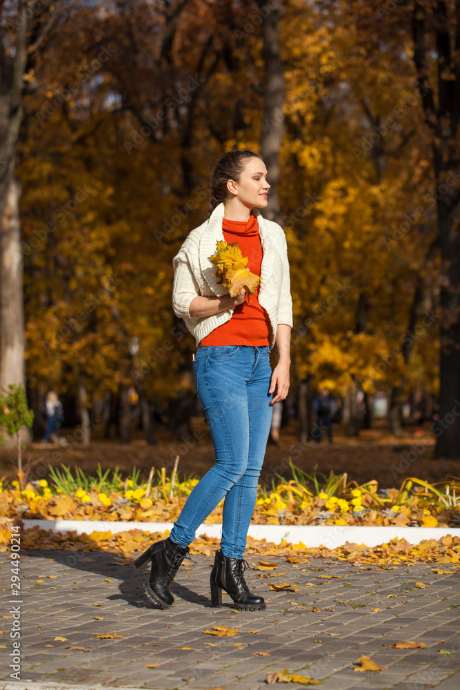 Young beautiful woman in blue jeans posing in autumn park Young beautiful woman in blue jeans posing in autumn park