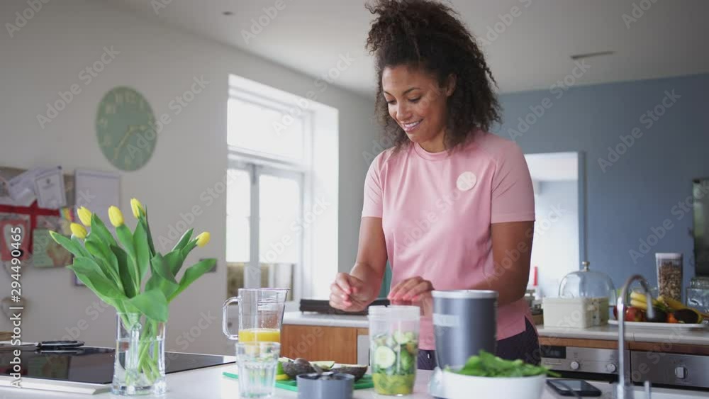 Woman Making Healthy Juice Drink With Fresh Ingredients In Electric Juicer After Exercise Woman Making Healthy Juice Drink With Fresh Ingredients In Electric Juicer After Exercise