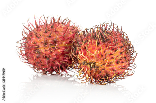 Group of two whole unpeeled fresh red rambutan isolated on white background