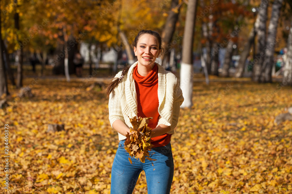 Young beautiful woman in blue jeans posing in autumn park Young beautiful woman in blue jeans posing in autumn park