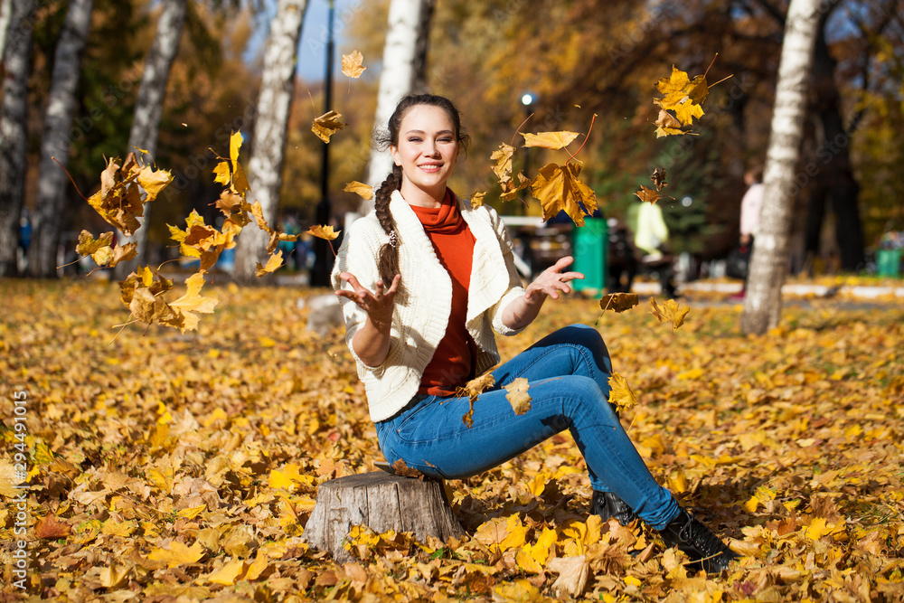 Young beautiful woman in blue jeans posing in autumn park Young beautiful woman in blue jeans posing in autumn park
