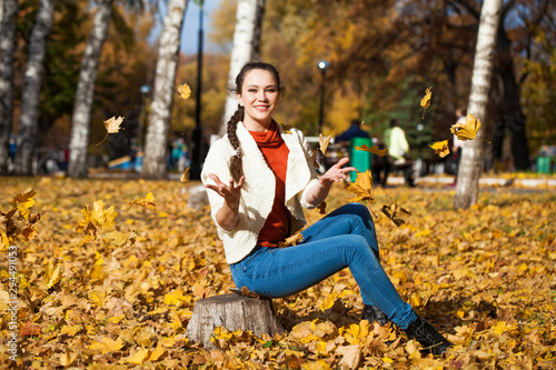 Young beautiful woman in blue jeans posing in autumn park