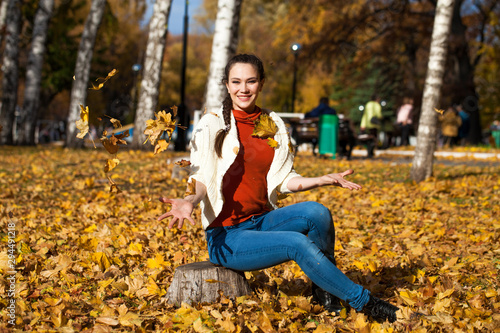 Young beautiful woman in blue jeans posing in autumn park