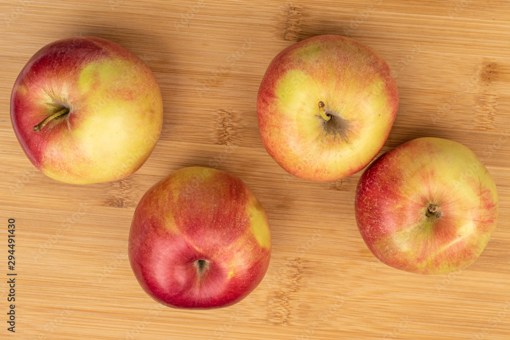 Group of four whole red apple jonagold flatlay on light wood Group of four whole red apple jonagold flatlay on light wood