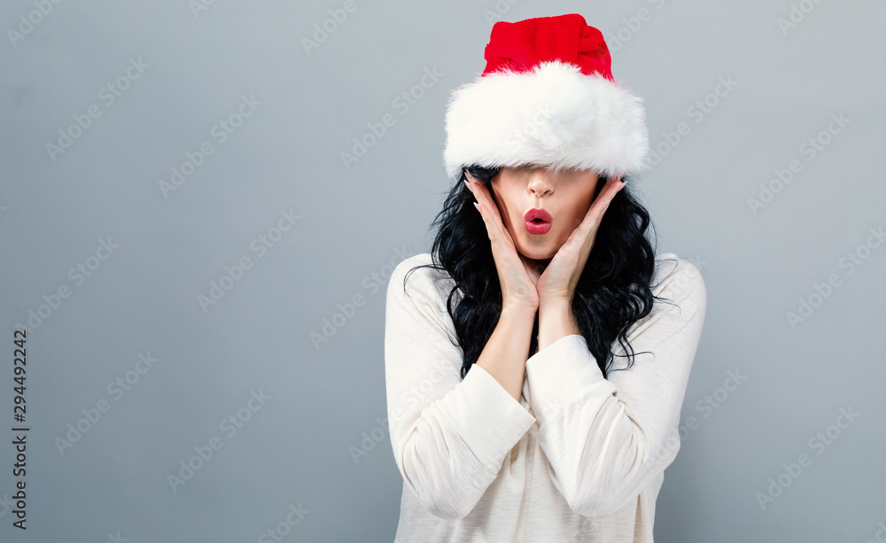 Woman with a Santa hat pulled over her eyes on a gray background Woman with a Santa hat pulled over her eyes on a gray background