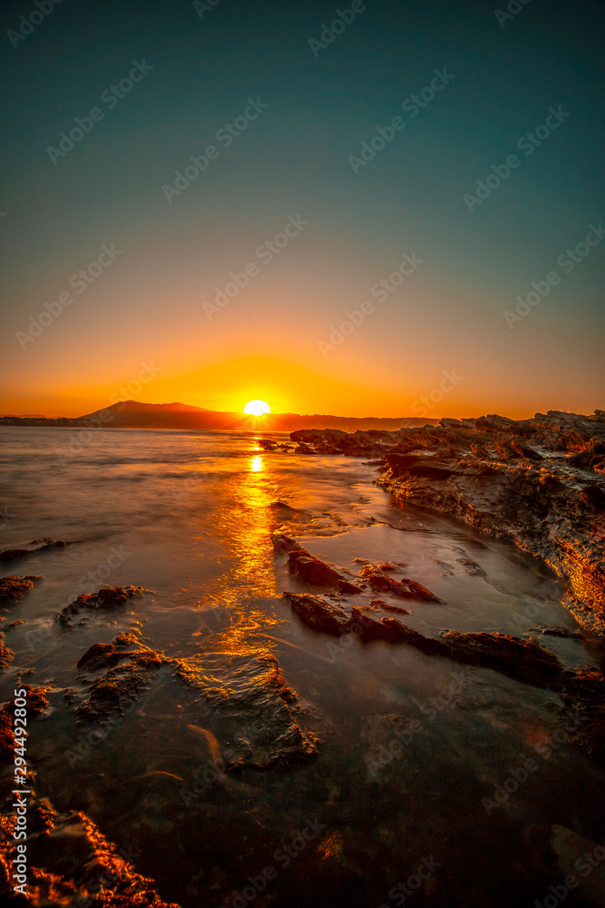 Obraz premium Last moments of the sun from the rocks of Hendaye on an orange sunset. France