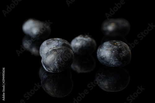 Group of five whole fresh blue blueberry isolated on black glass