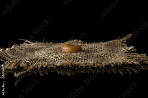 One whole caramel brown candy with jute fabric isolated on black glass photo