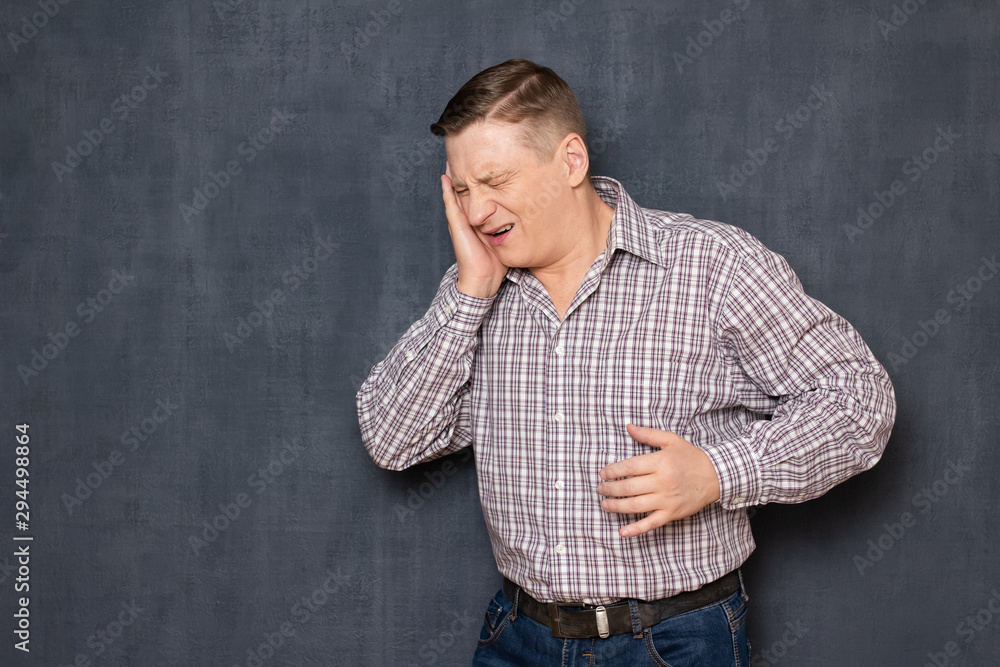 Portrait of unhappy young man suffering severe toothache