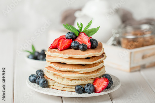 Classic american pancakes with fresh berry on white wood background. Summer homemade breakfast. photo