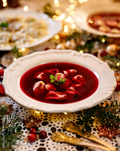 Christmas beetroot soup, borscht with small dumplings with mushroom filling in a ceramic white plate on a holiday table.Traditional Christmas eve dish in Poland.  photo