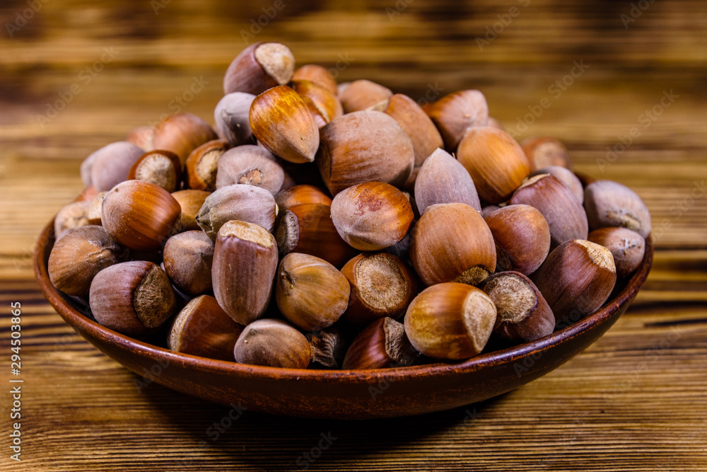 Plate with pile of hazelnuts on a wooden table