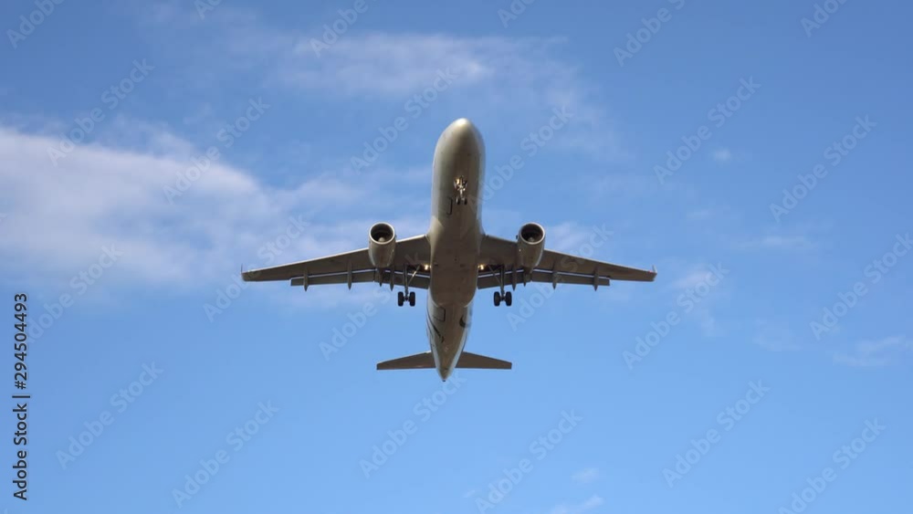 Modern passenger plane flies overhead, exactly in the center of the frame. In the background there is a beautiful blue sky and white clouds. The airplane is landing, taking off. Ultra HD stock footage Modern passenger plane flies overhead, exactly in the center of the frame. In the background there is a beautiful blue sky and white clouds. The airplane is landing, taking off. Ultra HD stock footage