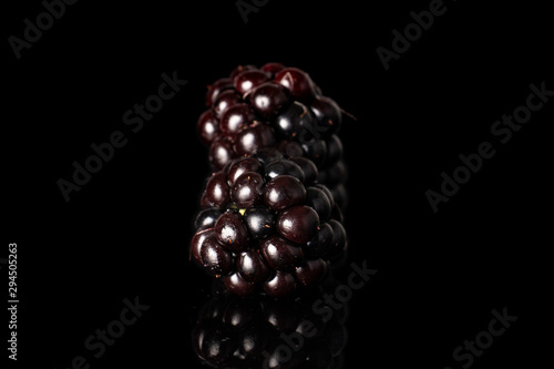 Group of two whole fresh black blackberry isolated on black glass
