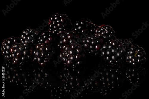 Lot of whole fresh black blackberry heap isolated on black glass photo