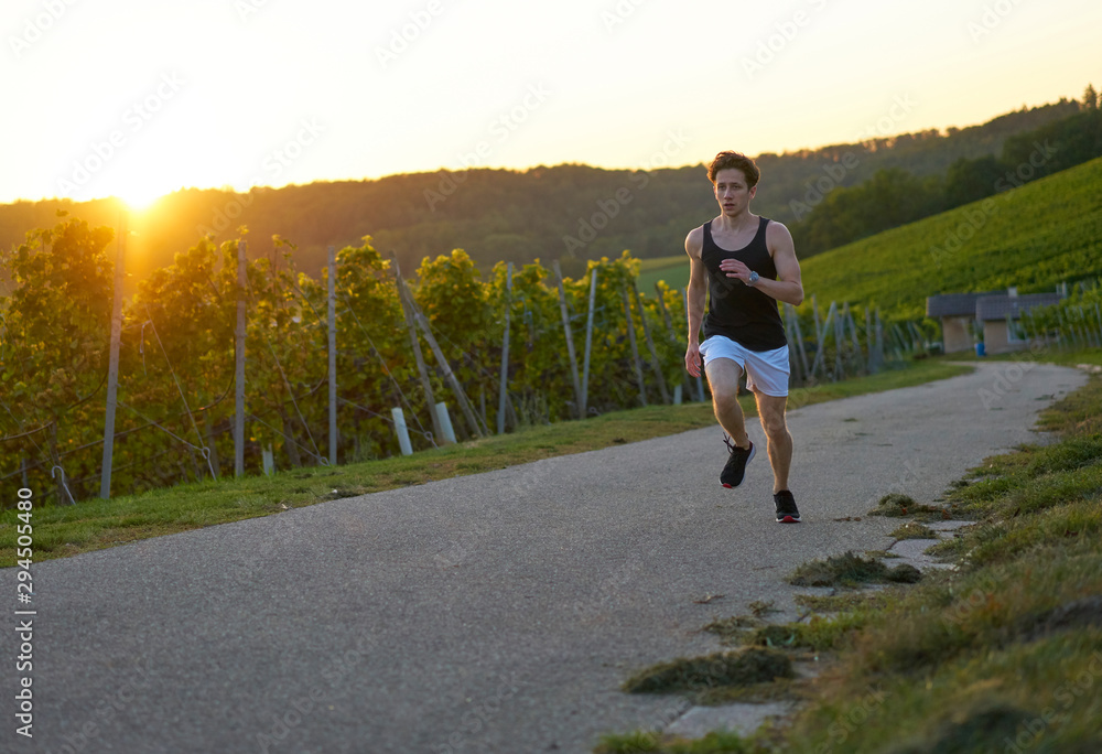 dynamic jogger in green nature during sunset