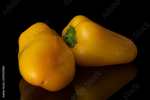 Group of two whole arranged fresh pepper isolated on black glass photo